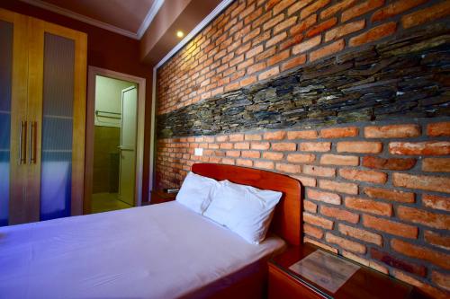 a brick wall with a bed in a bedroom at Menis Haus Rooms in Nea Vrasna