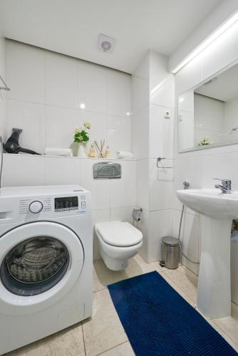 a white bathroom with a washing machine and a sink at Beautiful Seaside Apartments in Tavira