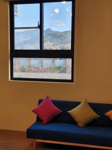 a blue couch with four pillows in front of a window at Clare Holiday B&B in Checheng