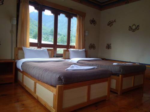 two beds in a room with a window at Nirvana Lodge in Paro
