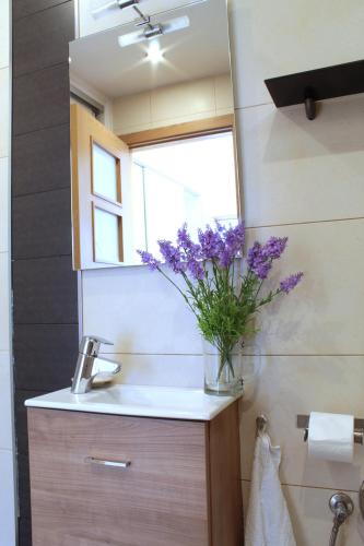 a bathroom with a sink with a vase of purple flowers at NEW ColonyClub in Puerto del Carmen