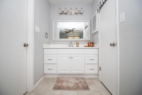 uma casa de banho branca com um lavatório e um espelho em Cozy cottage feel, 5 mins from Ft. Bragg em Fayetteville