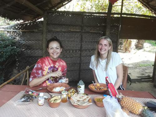 dos mujeres sentadas en una mesa con comida en Ekamuthu Homestay, en Dikwella
