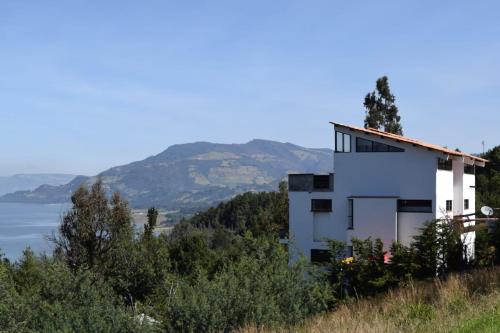 a white house on a hill with a view of the water at Abadia de Tomine in Guatavita
