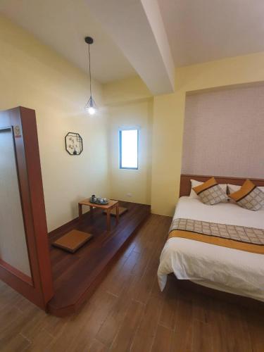 a bedroom with a large bed and a table at Clare Holiday B&B in Checheng