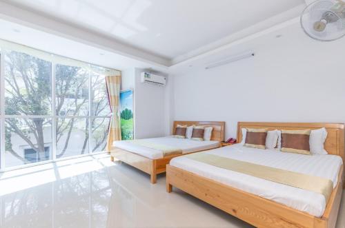 a bedroom with two beds and a large window at RIO Hotel and Apartment in Vung Tau