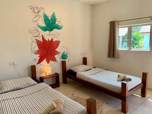 a bedroom with two beds and a painting on the wall at Kawah Padi Garden Villa Langkawi in Kuah