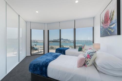 two beds in a room with a view of the ocean at Astra Apartments Newcastle in Newcastle