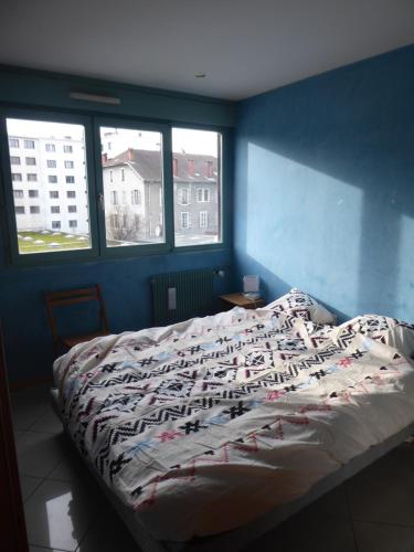 łóżko w pokoju z niebieskimi ścianami i oknami w obiekcie Chambre dans un appartement Annecy Gare-Centre w Annecy