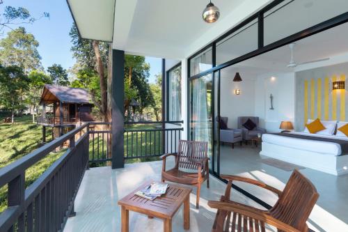 a room with a balcony with a bed and chairs at The Farm Resorts in Hatton