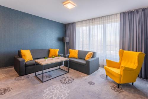 a living room with a couch and a table and a chair at Hotel Lantier Wellness & Spa in Bytom