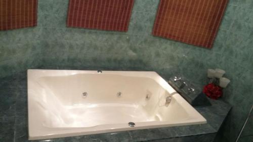 a white bath tub in a bathroom with green tiles at residencia 2 in Mazatlán