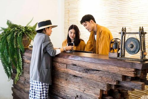 eine Gruppe von drei Personen, die ein Handy ansehen in der Unterkunft NORN Nimman13 Boutique Hotel Chiang Mai in Chiang Mai