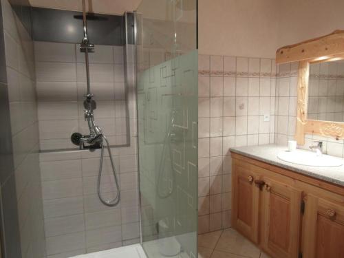 een badkamer met een glazen douche en een wastafel bij Gîte Les Sauvasses in Puy-Sanières