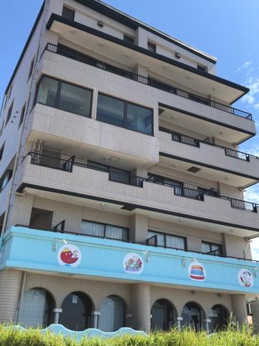 a tall apartment building with a sign in front of it at Support Inn Minami-Chita Annex Hamachaya in Minamichita