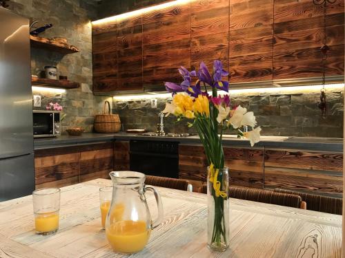 a vase of flowers on a table with orange juice at Apartmán Luky in Vyšné Ružbachy