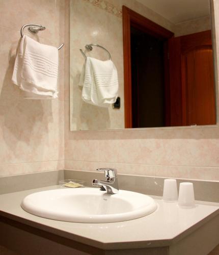a bathroom with a sink and a mirror and towels at Hostal Cafeteteria Goya in Barbastro