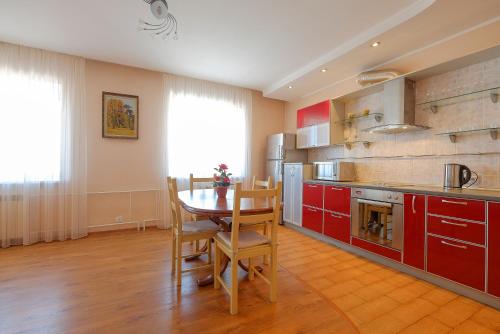 a kitchen with red cabinets and a table and chairs at OK! Алексея Беленца 6 in Tomsk