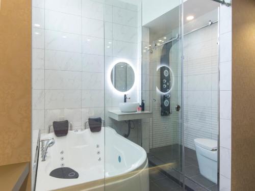 a bathroom with a tub and a toilet and a mirror at Top Garden Hotel in Hutan Melintang