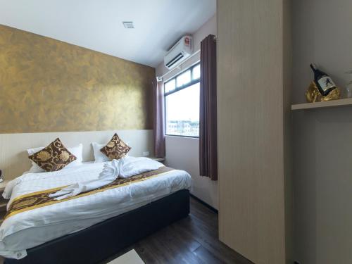a small bedroom with a bed with a window at Top Garden Hotel in Hutan Melintang
