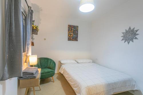 1 dormitorio con 1 cama y 1 silla verde en The Private House רשת הבית הפרטי, en Beer Sheva