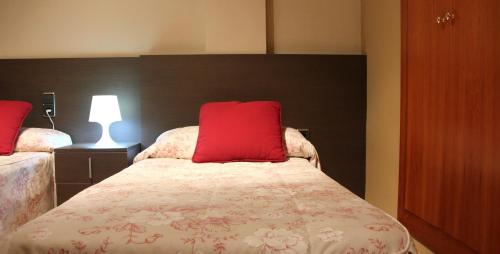 a bedroom with a bed with a red pillow on it at Hostal Cafeteteria Goya in Barbastro