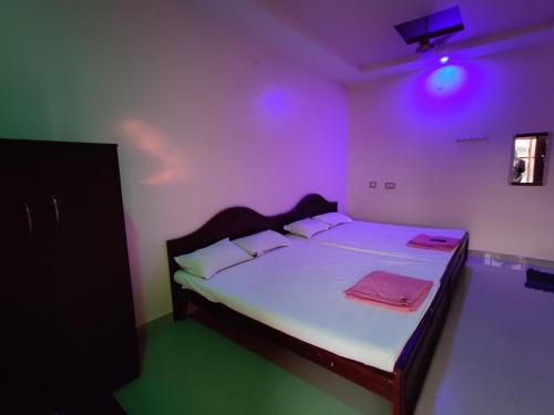 ein Schlafzimmer mit einem Bett mit violettem Licht in der Unterkunft Sakthimurugan residency in Erode