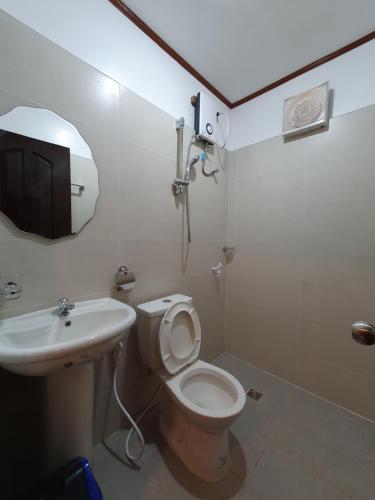 y baño con aseo, lavabo y espejo. en AMARAV Pension House Nacpan El Nido en El Nido