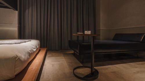a bedroom with a bed and a bench and a table at Hotel Aoka Kamigoto in Shinkamigoto