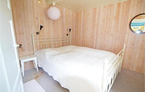1 Bedroom Awesome Home In Nrre Nebel في Nymindegab: غرفة نوم بسرير ابيض في جدار خشبي