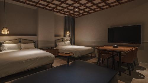 a hotel room with two beds and a flat screen tv at Hotel Aoka Kamigoto in Shinkamigoto