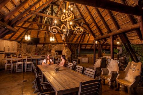 two women sitting at a large wooden table in a barn at @Nature Luxury Cottages in Nelspruit