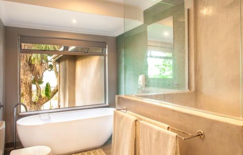 a bathroom with a bath tub and a window at @Nature Luxury Cottages in Nelspruit