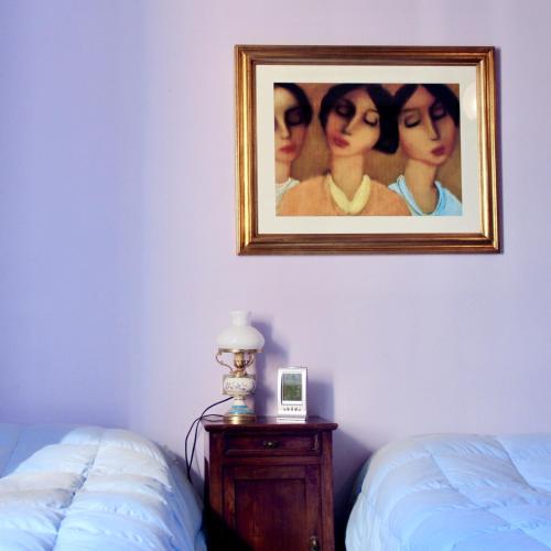 a painting of three women on a wall next to a bed at CAMINATA 415 in Fiorenzuola dʼArda