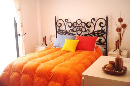1 dormitorio con 1 cama de color naranja y almohadas coloridas en Casa El Paseo, en Arriate