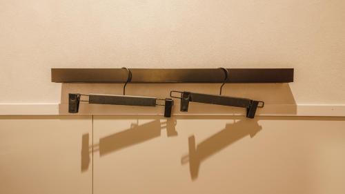 a shelf with two black hooks on a wall at Hotel Aoka Kamigoto in Shinkamigoto