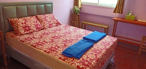 a bed with a red blanket and a blue pillow at santo house in Bangkok
