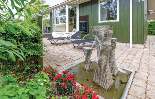 a patio with two wicker chairs and flowers in front of a house at Three-Bedroom Holiday Home In Follenslev in Føllenslev