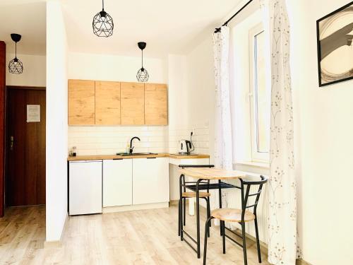 a kitchen with white cabinets and a table and chairs at Apartament Salton in Bochnia
