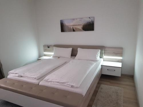 a bed with white sheets and pillows in a room at Pension Hofer in Bad Berneck im Fichtelgebirge