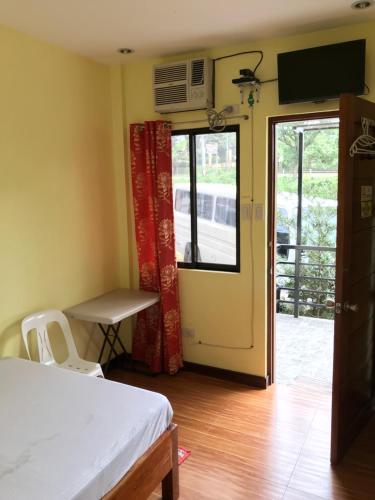 a room with a bed and a table and a window at Jhunlyn Rooms for Rent Tagaytay in Tagaytay