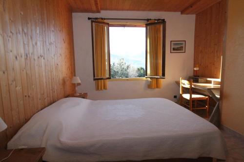 Un dormitorio con una gran cama blanca y una ventana en Le Vieux Chalet, en Embrun