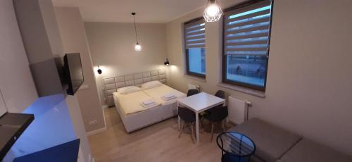 Habitación pequeña con cama, mesa y ventana en Garden Gates and Sadowa Apartments en Gdansk