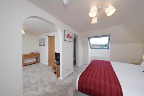 a bedroom with a large bed with a red blanket at Woodlands Bed & Breakfast in Drumnadrochit