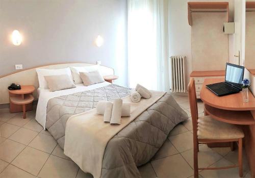 a bedroom with a bed and a desk with a laptop at Hotel Prestige in Rimini