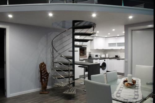 a spiral staircase in a kitchen with a table and chairs at Cottage Quinze & Apartment with Swimming pool in Ponta Delgada
