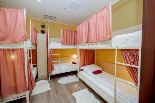 Cette chambre comprend 4 lits superposés dotés de rideaux rouges. dans l'établissement High Level - has a great history, quiet calm and cozy place for only 24 guests!, à Moscou