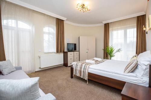 sypialnia z 2 łóżkami, telewizorem i oknami w obiekcie Villa Rosa w Hajduszoboszlo