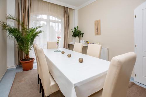 a white dining room with a white table and chairs at Villa Rosa in Hajdúszoboszló