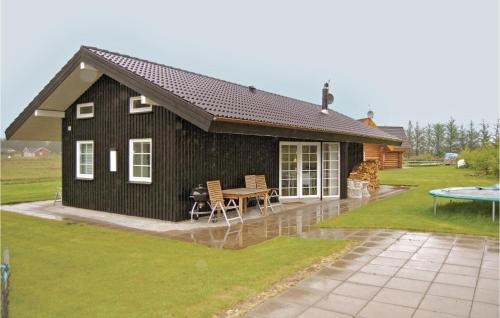 a black house with a table and chairs in the yard at Holiday Home Egelunden Ansager I in Ansager